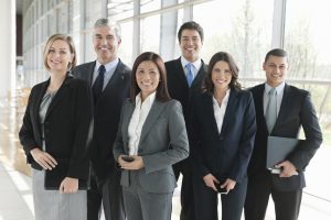 Organized group portrait of multiethnic business team standing together in office. Horizontal shot.